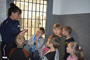 dzieci zwiedzają komendę policji w towarzystwie policjantki