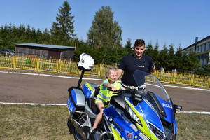 dziecko na policyjnym motocyklu, obok policjant