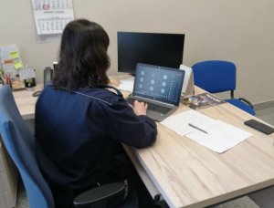 policjantka w czasie lekcji online  siedzi przed ustawionym na biurku laptopie