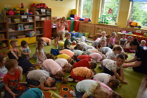 spotkanie z dziećmi w PP nr 2 w Bartoszycach, policjanta uczy dzieci pozycji żółwia