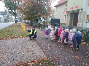 spotkanie dzielnicowego z przedszkolakami z Sępopola, policjant przy przejściu dla pieszych z grupą dzieci